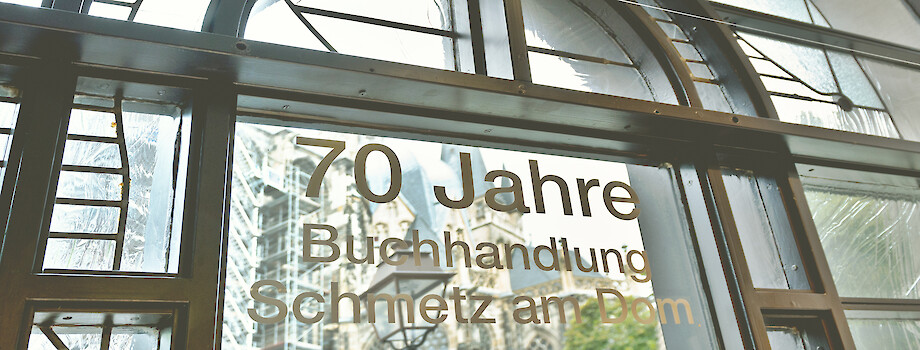buchhandlung-schmetz--heroimage--about_us-mirrored Buchhandlung Schmetz am Dom, Aachen: Blick durch ein Schaufenster